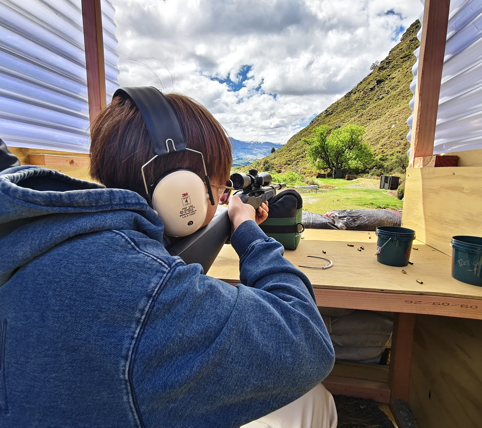 Rear view of a guest aiming a scoped rifle at the TopGuns outdoor range